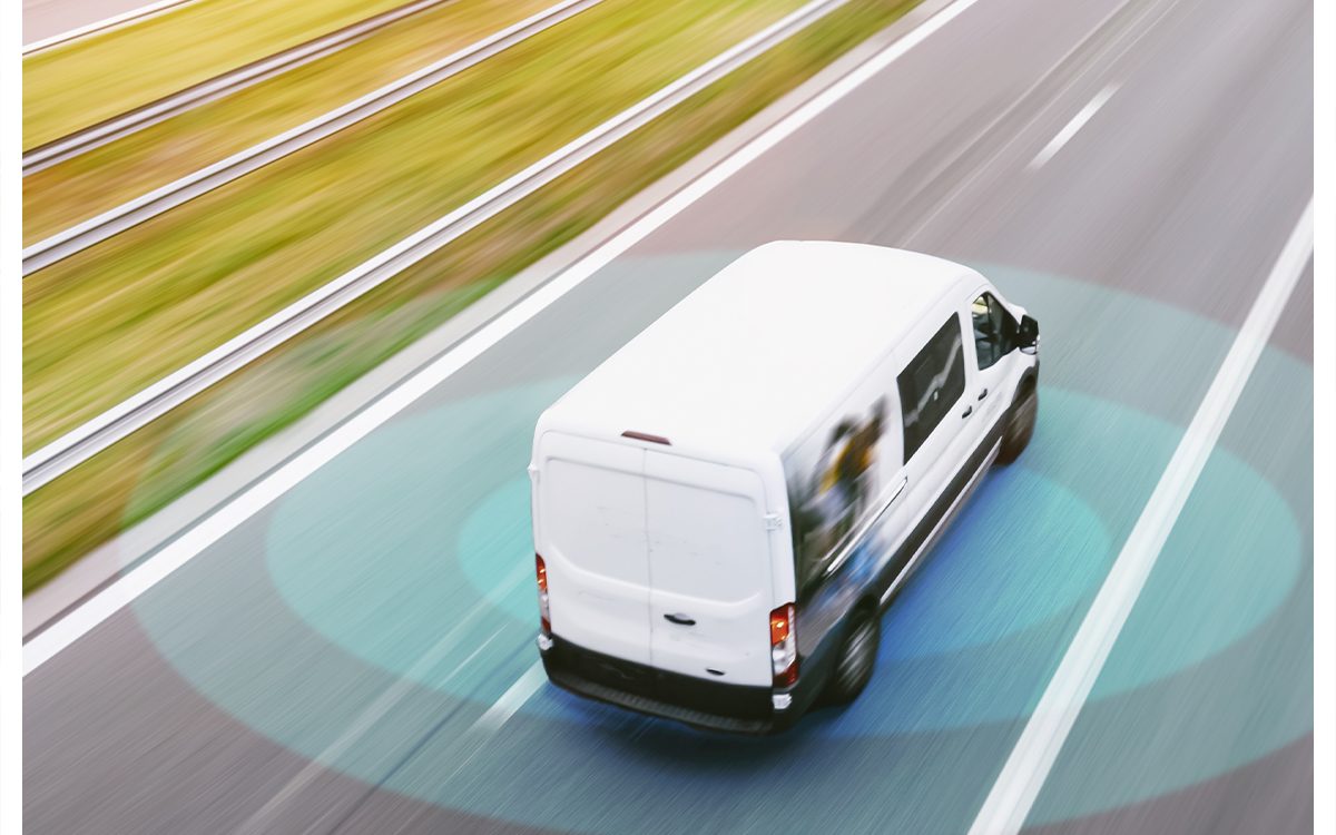 Biały samochód dostawczy z tachografem jadący po drodze